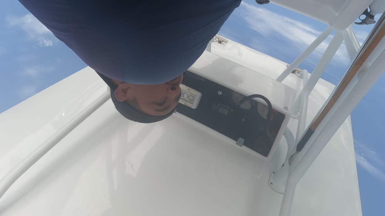 At 0:02, the person's head and shoulder remain near the top edge of the inverted frame while the white deck and black controls sit below the sky in Baja California, Mexico.