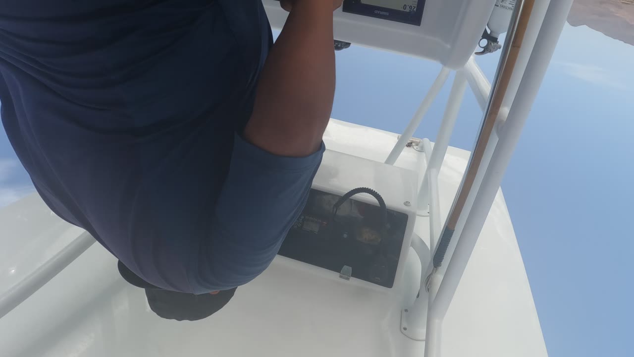 In Baja California, Mexico, the man remains bent over the boat console, with his back centered and the control panel partly visible below his arm.
