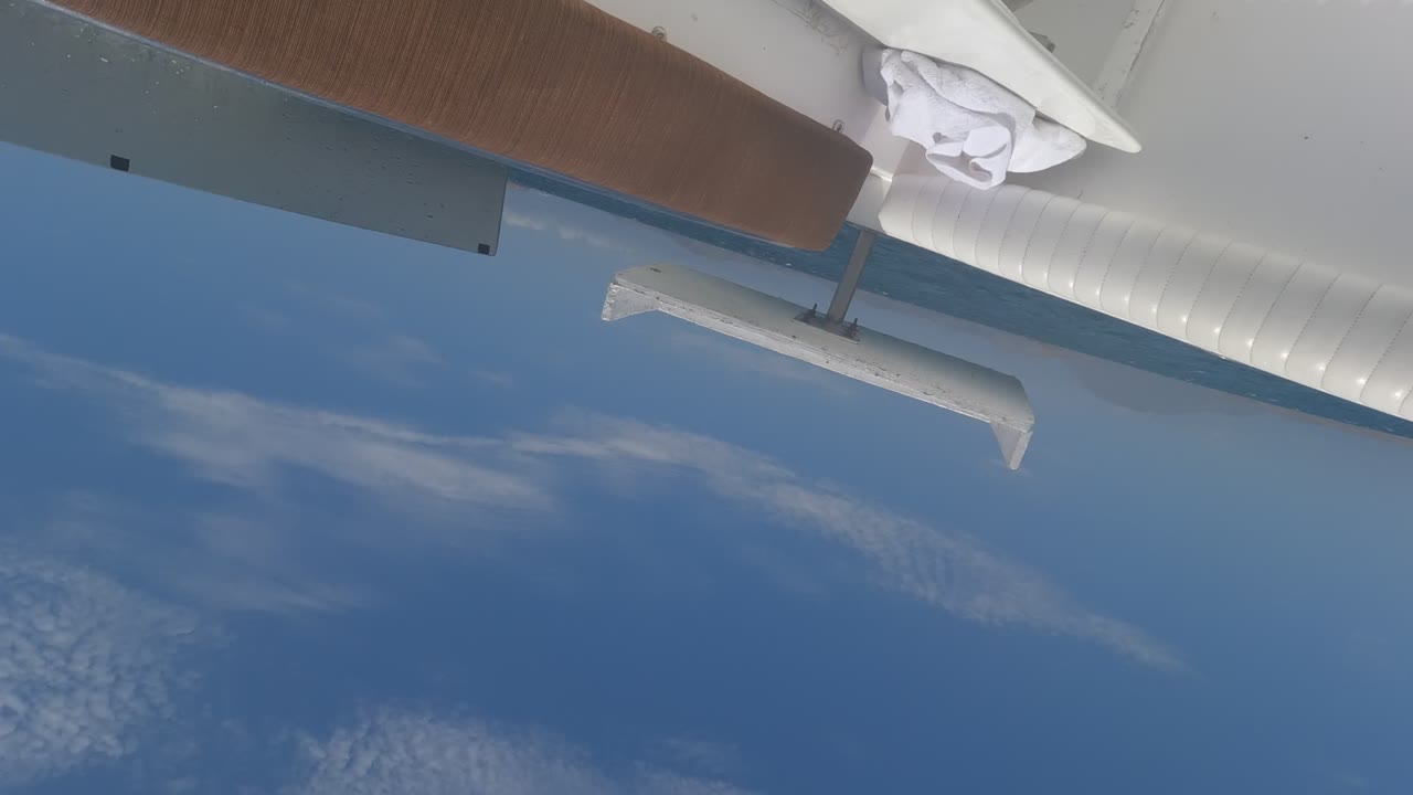 Baja California, Mexico in-flight view with a white aircraft wing and strut above blue sky and scattered clouds, no visible people.
