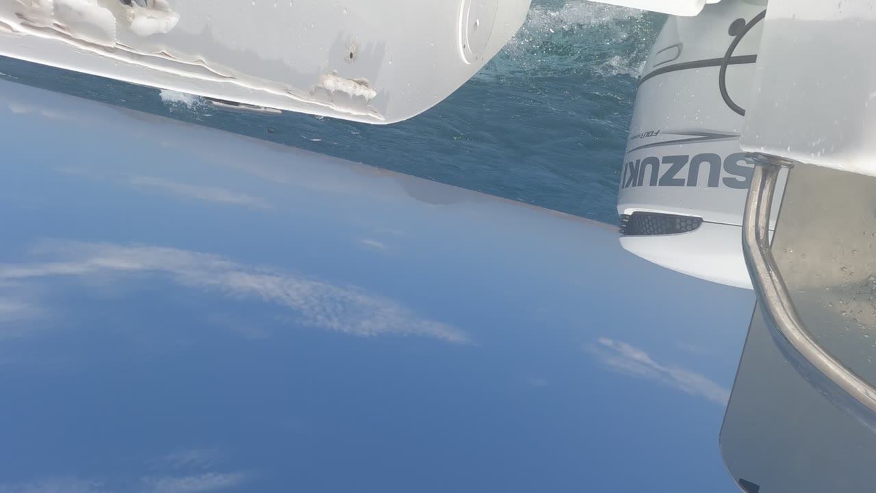 White boat hull above blue ocean with the outboard partly out of frame.