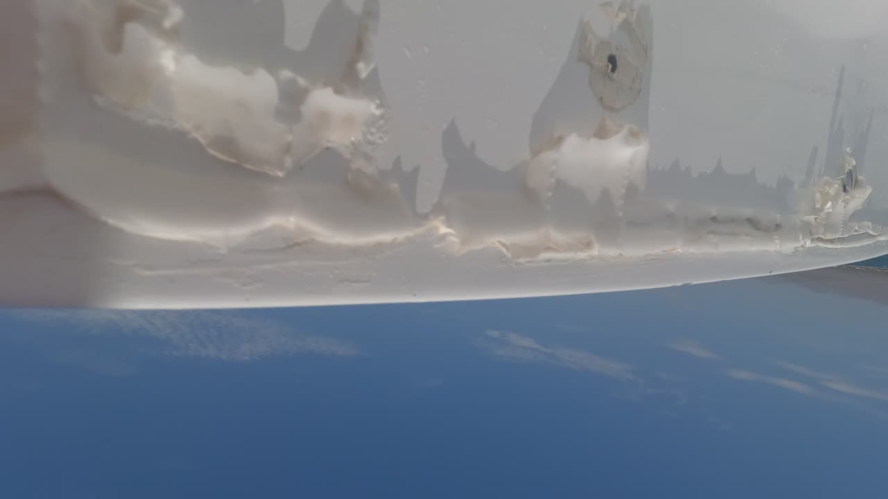 Low-angle Baja California ship view with the white hull across the top, blue water below, faint cloud reflections, and no visible people.