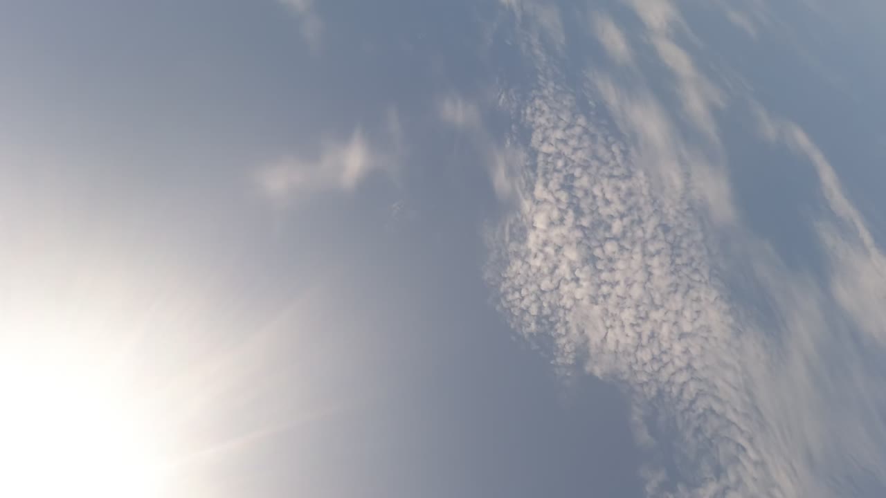 Tilted sky view with clouds and a small strip of land