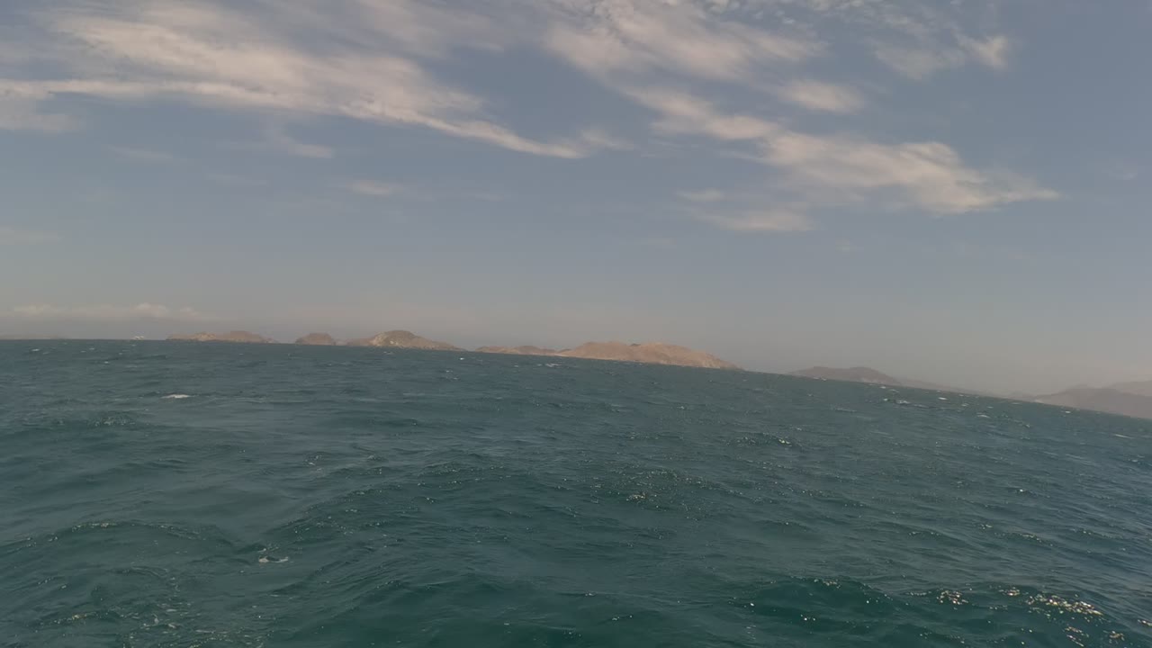 Baja California ocean view with a slanted horizon, low distant islands, blue-green waves, streaked clouds, and no visible people at 0:00.
