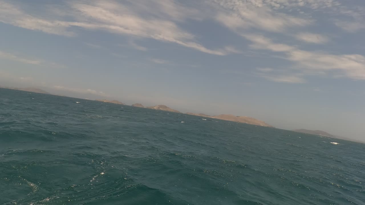 Open ocean surface with low islands on the horizon