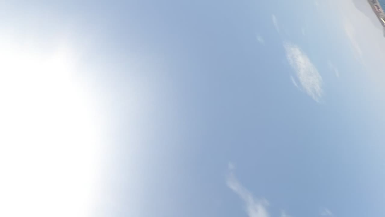 Bright sun and pale blue sky with a small boat edge near the top.