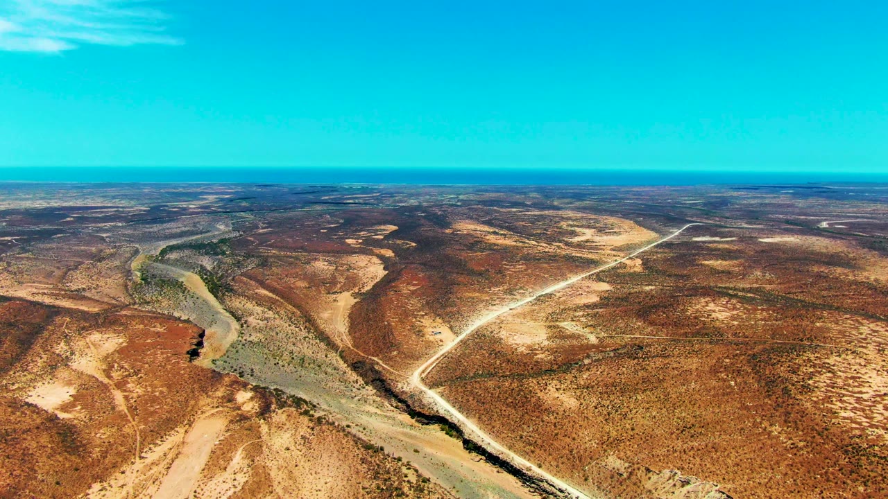 High desert aerial with river channel and crossing dirt roads.