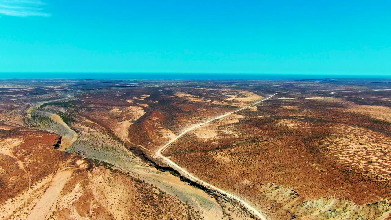 Desert river bend with pale roads crossing dry brown terrain.