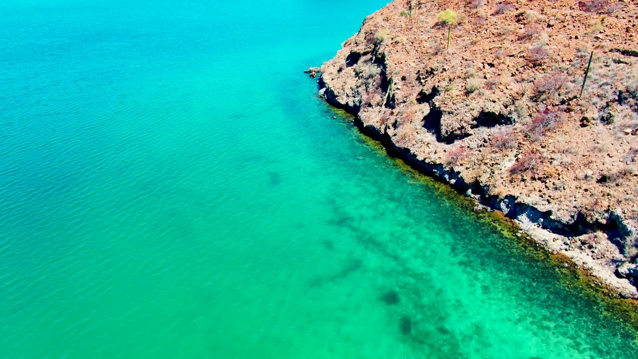 Clear green-blue water along a jagged rocky coast.