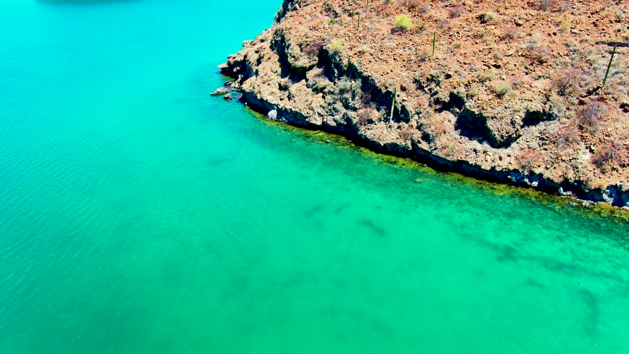 Turquoise water beside a rough rocky coast.