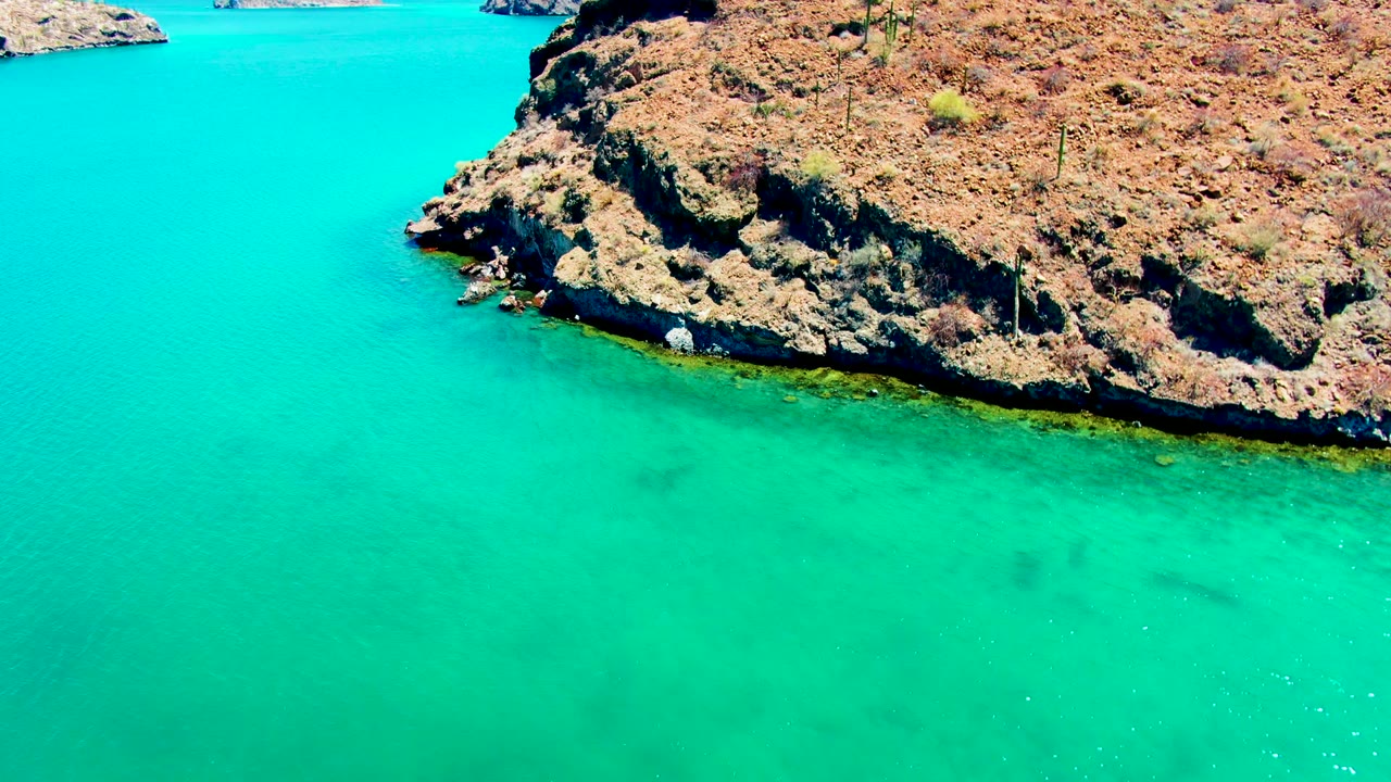 Rocky shoreline over clear green and turquoise water.