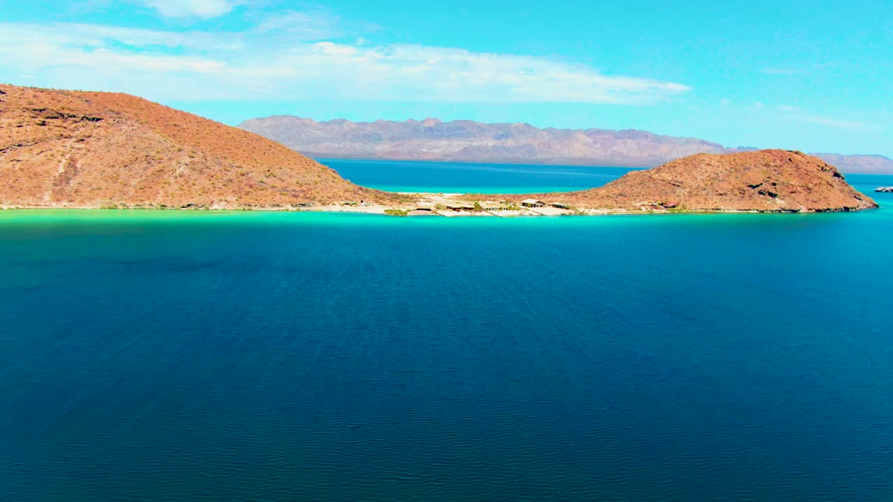 Rocky coastal channel with turquoise shallows, deep blue water, and mountain horizon.