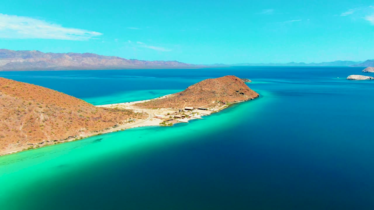 Aerial coastline with sandy beach, desert slope, and blue bay