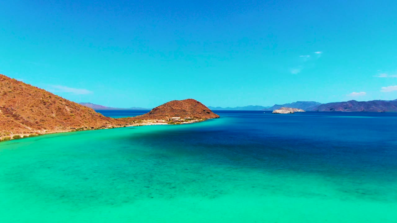 Clear shallow water below a rocky coastline and small offshore island.