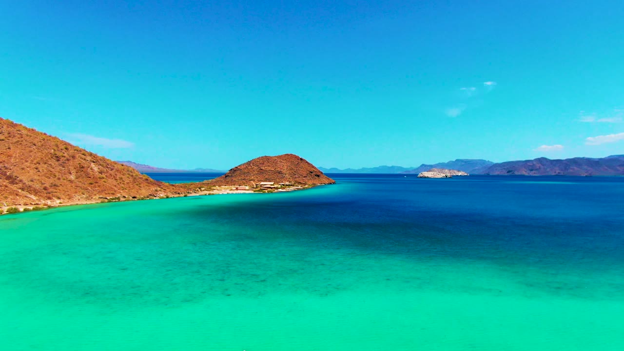 Wide bay scene with arid hillside, island, and calm blue water.