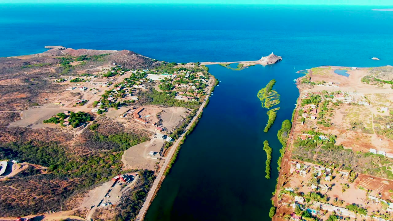 Wide aerial canal view with green algae patches and dry developed land on both sides.