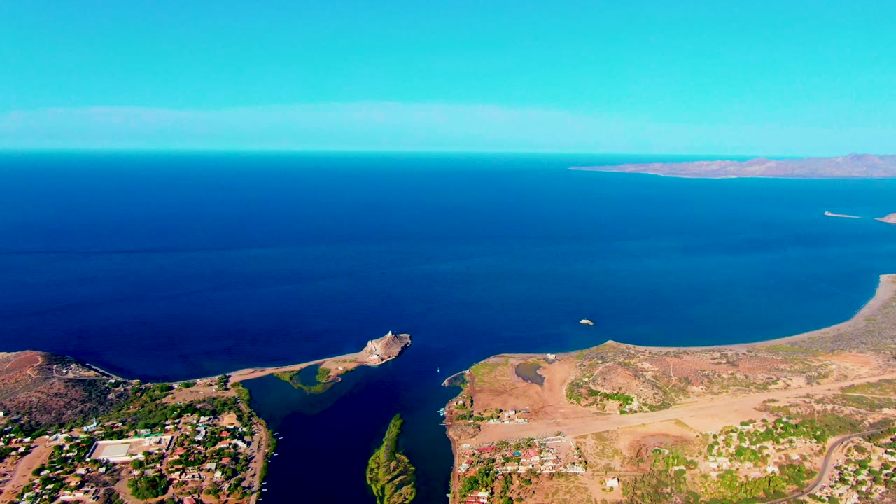 High aerial view of calm ocean, peninsula point, small boat, and dry coastal land.