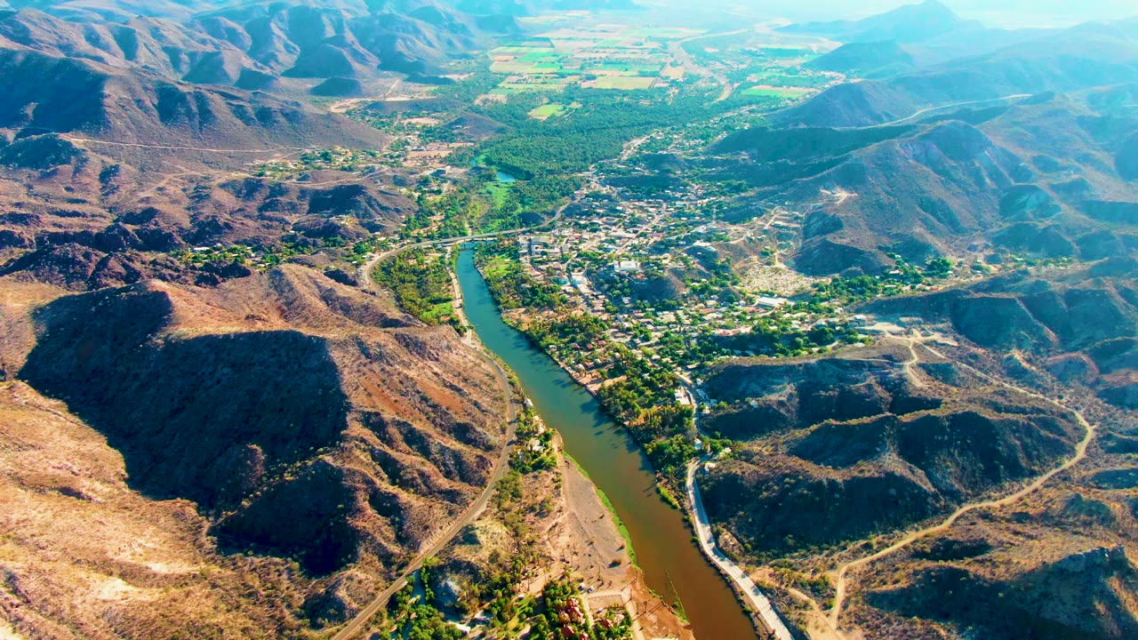 Aerial view of a river beside rugged hills and a settlement.