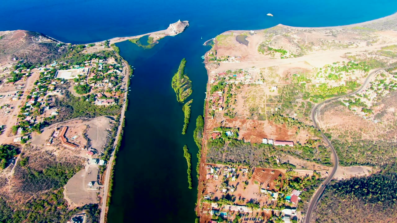 Overhead 4K frame of Mulege, Baja California Sur, Mexico, showing blue water along dry shoreline, scrub hills, scattered buildings, and no visible people.