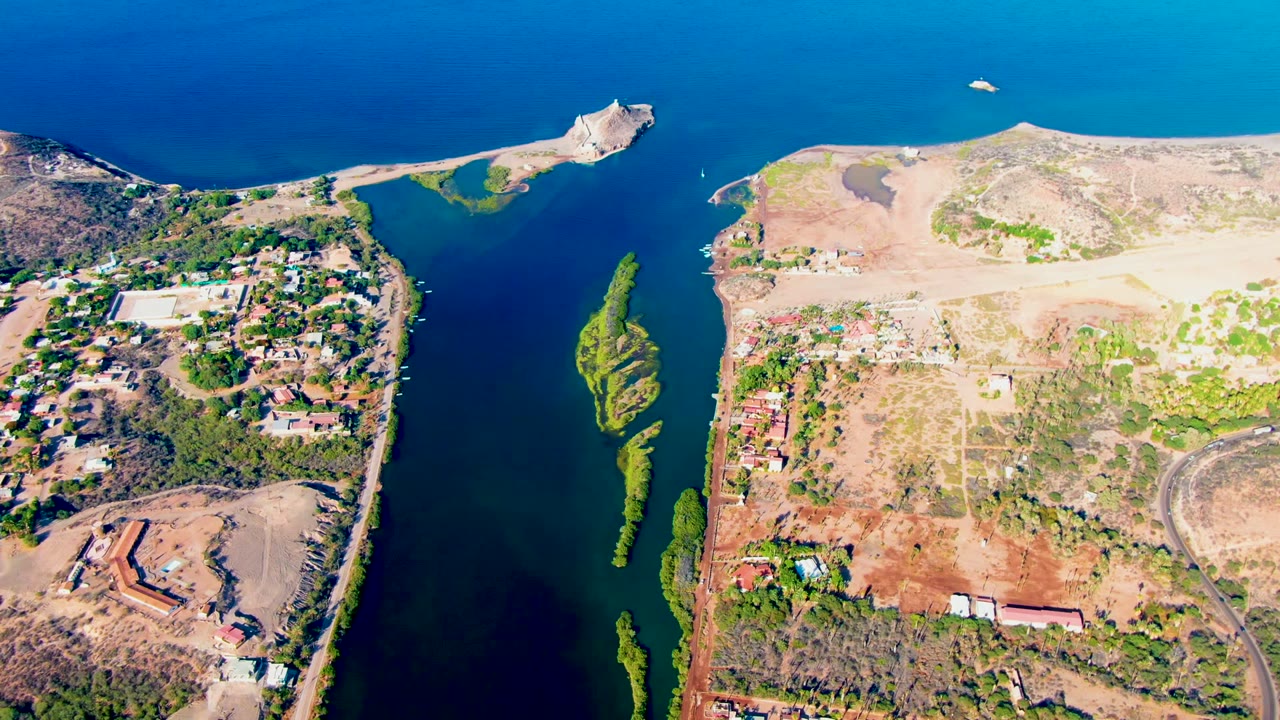 High aerial frame over Mulege, Baja California Sur, showing a blue inlet between a greener built-up left shore and an arid right shore, with no visible people.