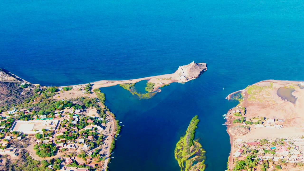 Drone view over a blue channel with a small island and arid shoreline.