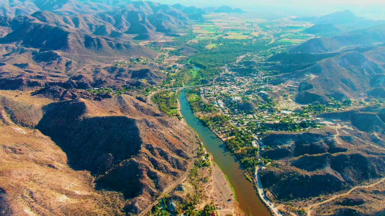 Drone view of a river beside a settlement in a dry mountain valley