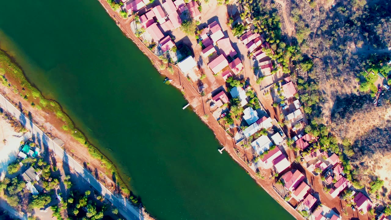Aerial view of riverside homes and dry hillside terrain.