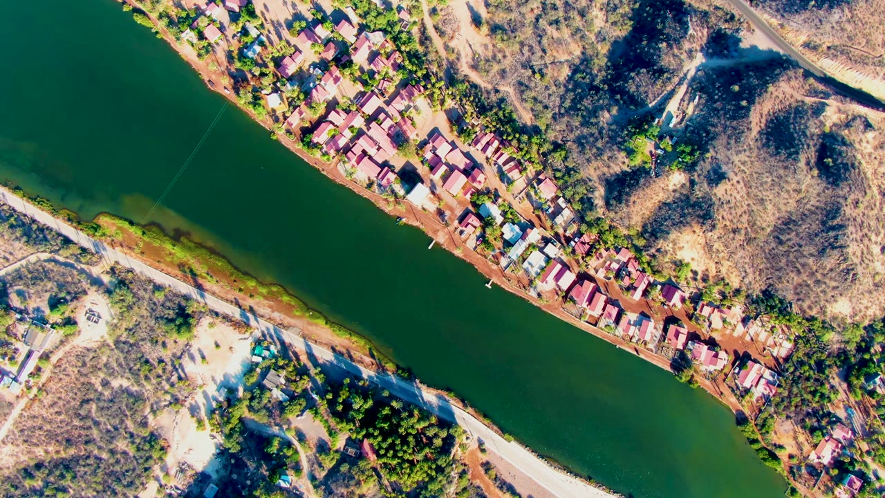 Drone view of green river and riverside houses