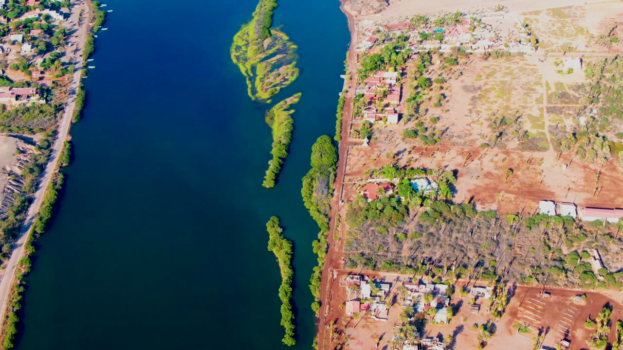 Aerial river water with exposed land and roadside buildings.