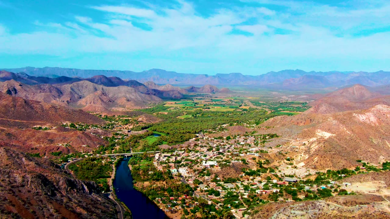 Aerial view of a winding river beside a town in a dry mountain valley.