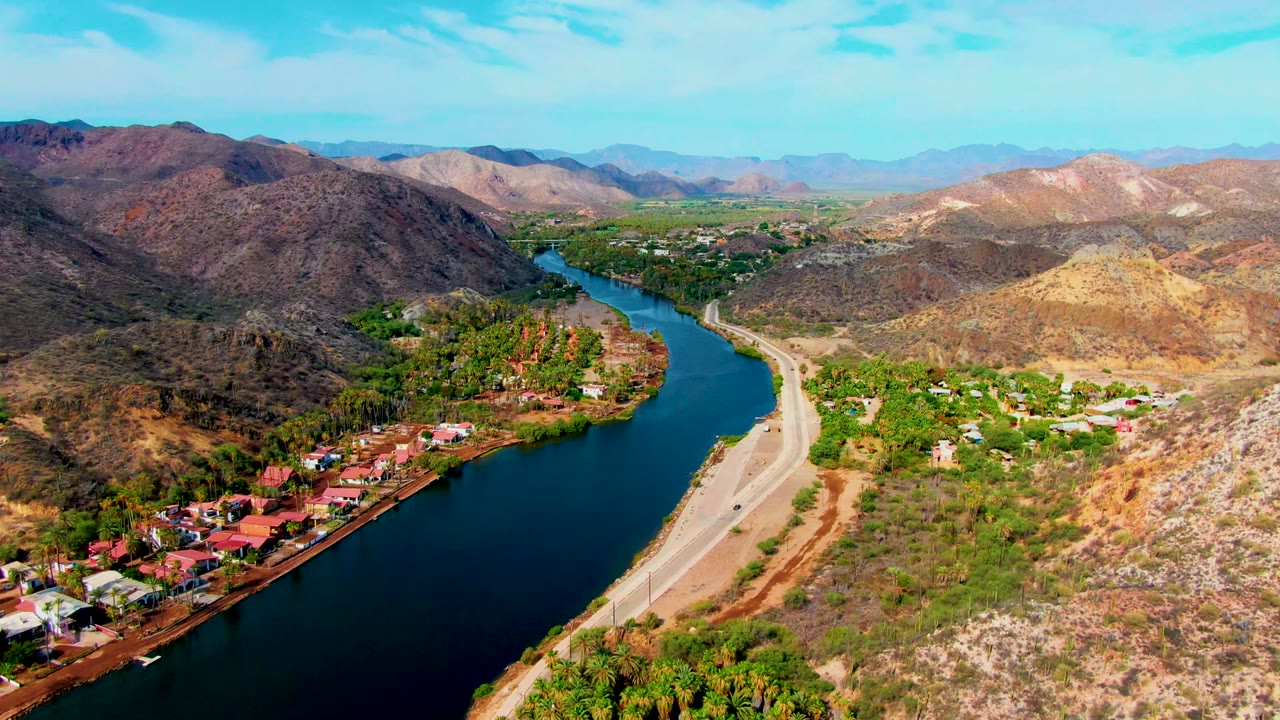 Drone view over a curving river and road in a mountain valley.