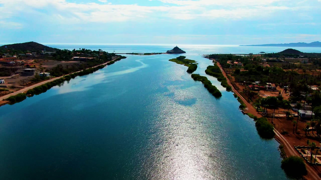 High aerial view of a calm water channel bordered by vegetation and roads.