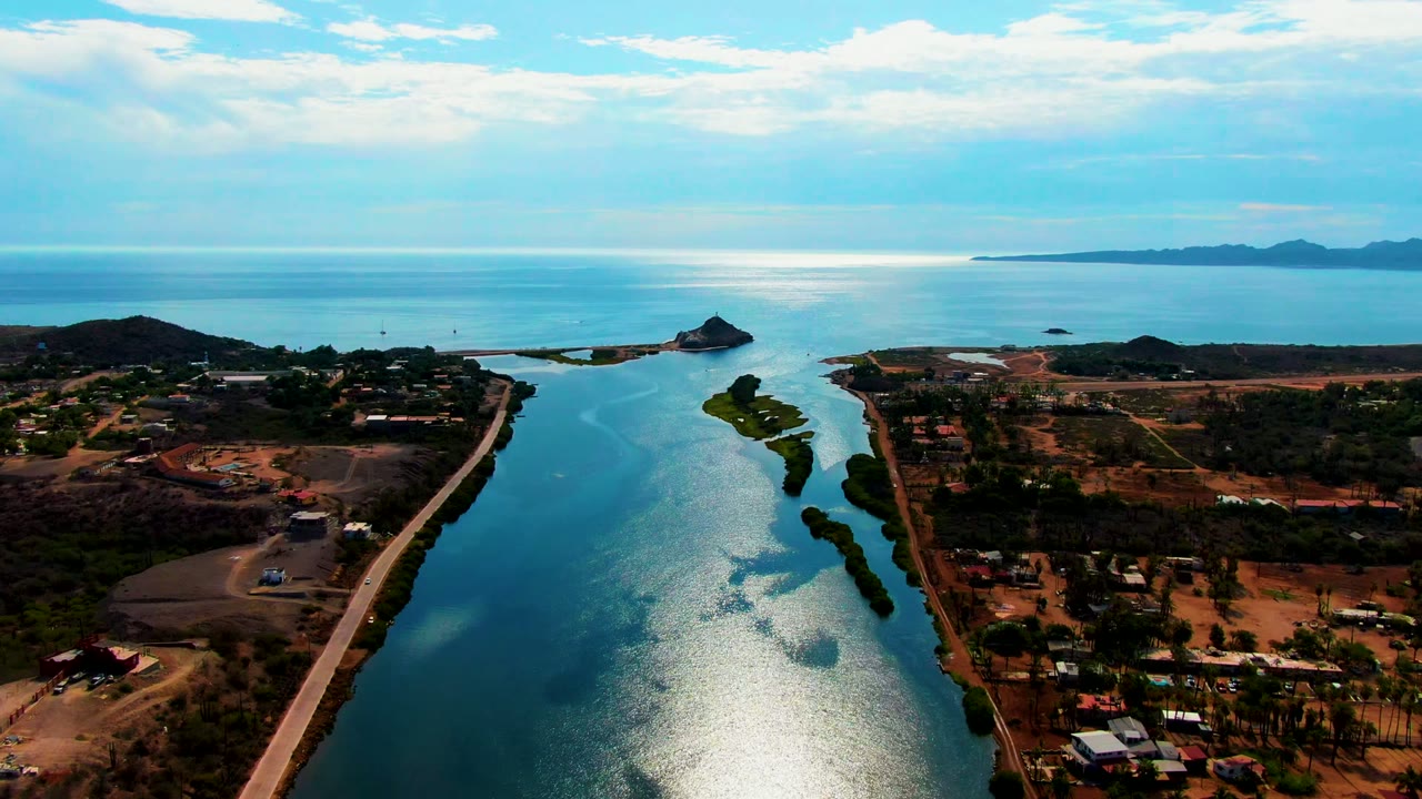 Wide drone view of the channel with road traffic routes and small buildings beside it.