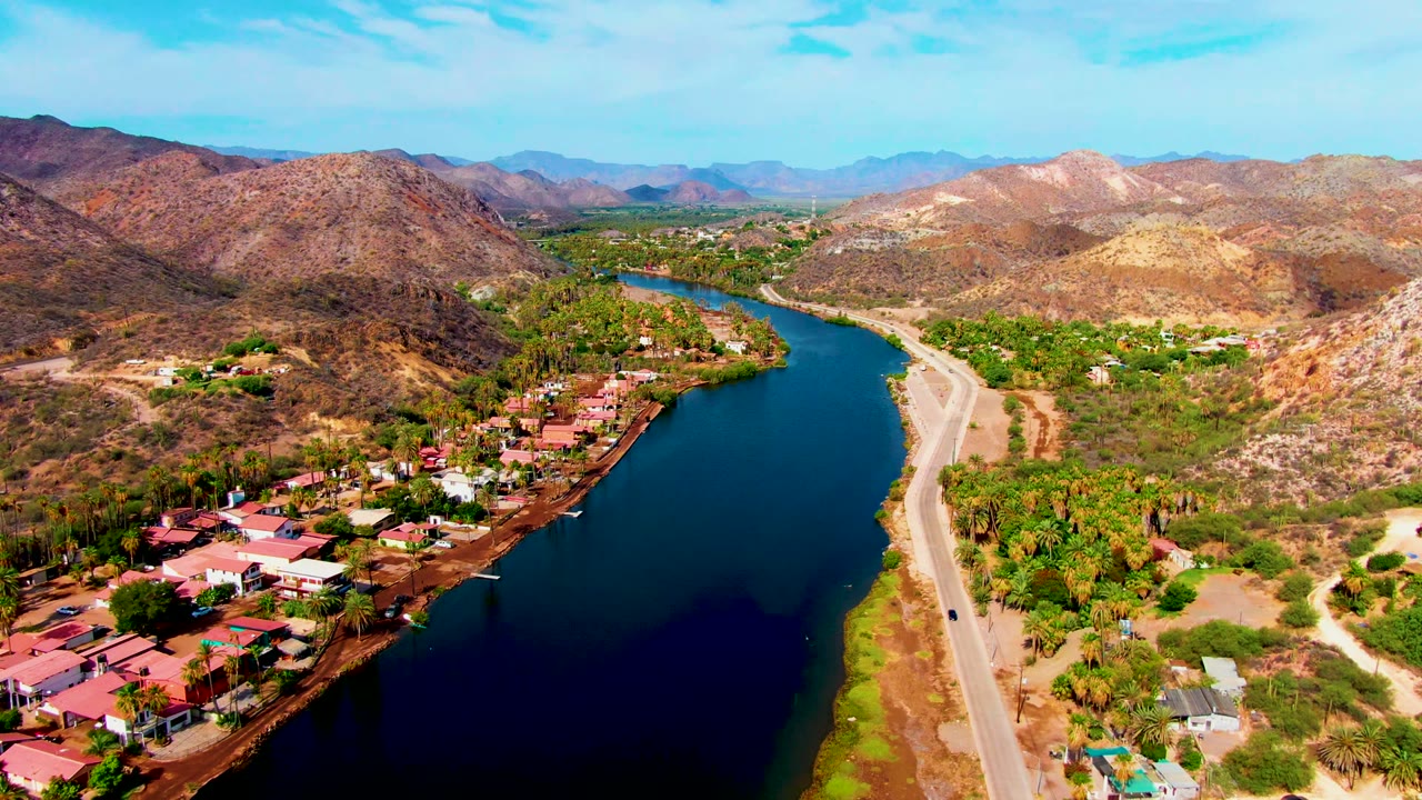 River, roadside houses, and mountains seen from above.