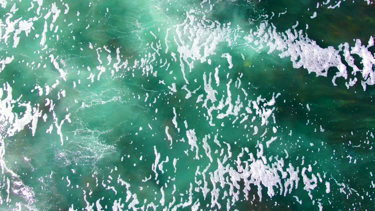 Green ocean surface with foamy white wave marks.