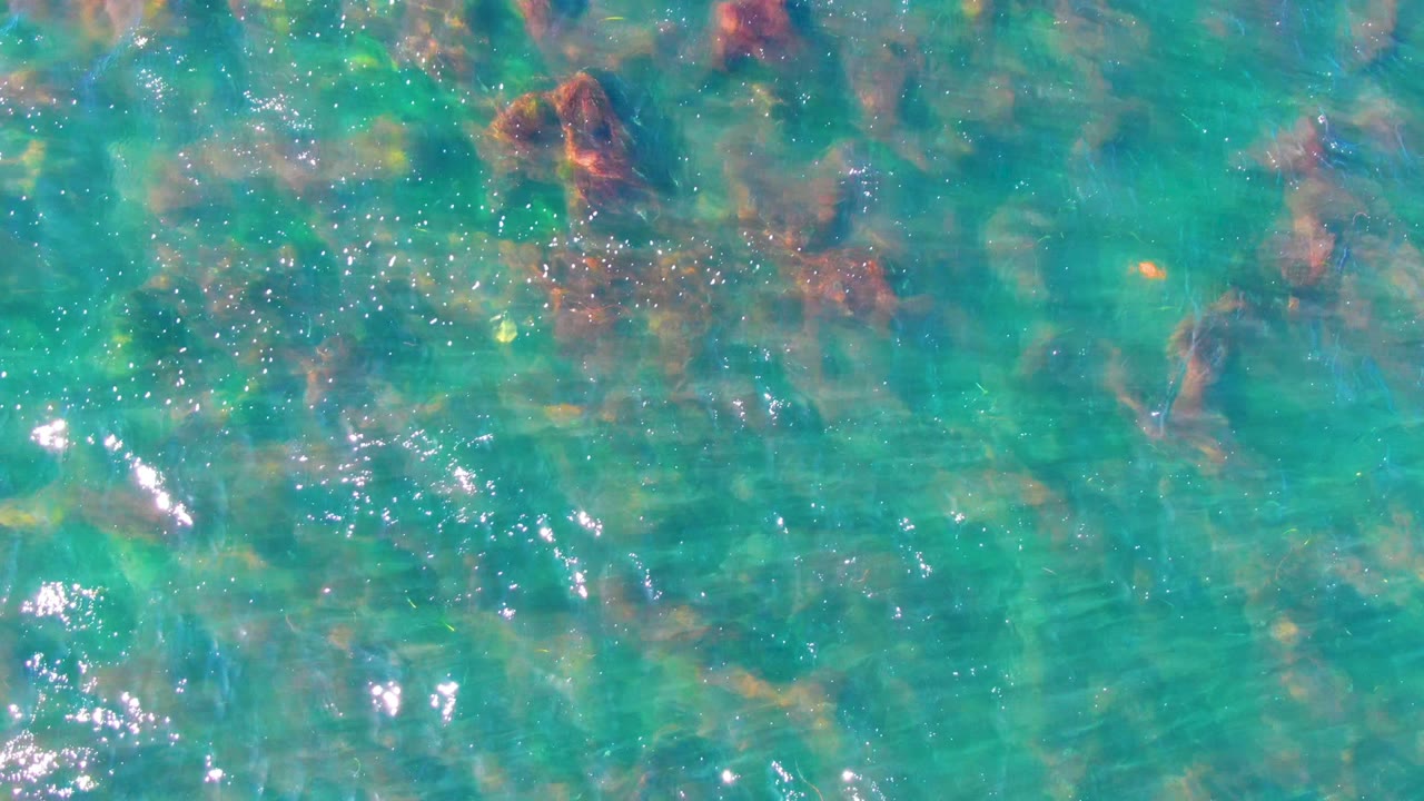 Clear water with bright reflections over submerged rocks