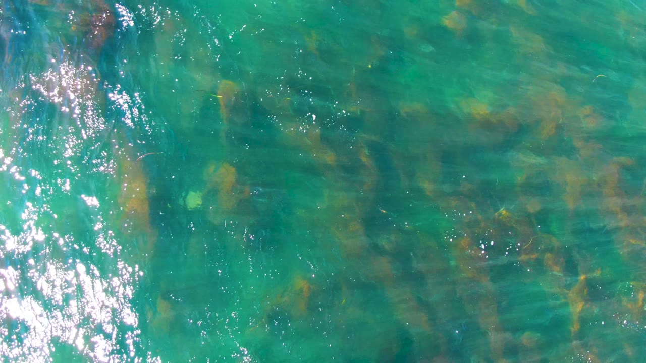 Clear green-blue water with ripples and submerged rocks