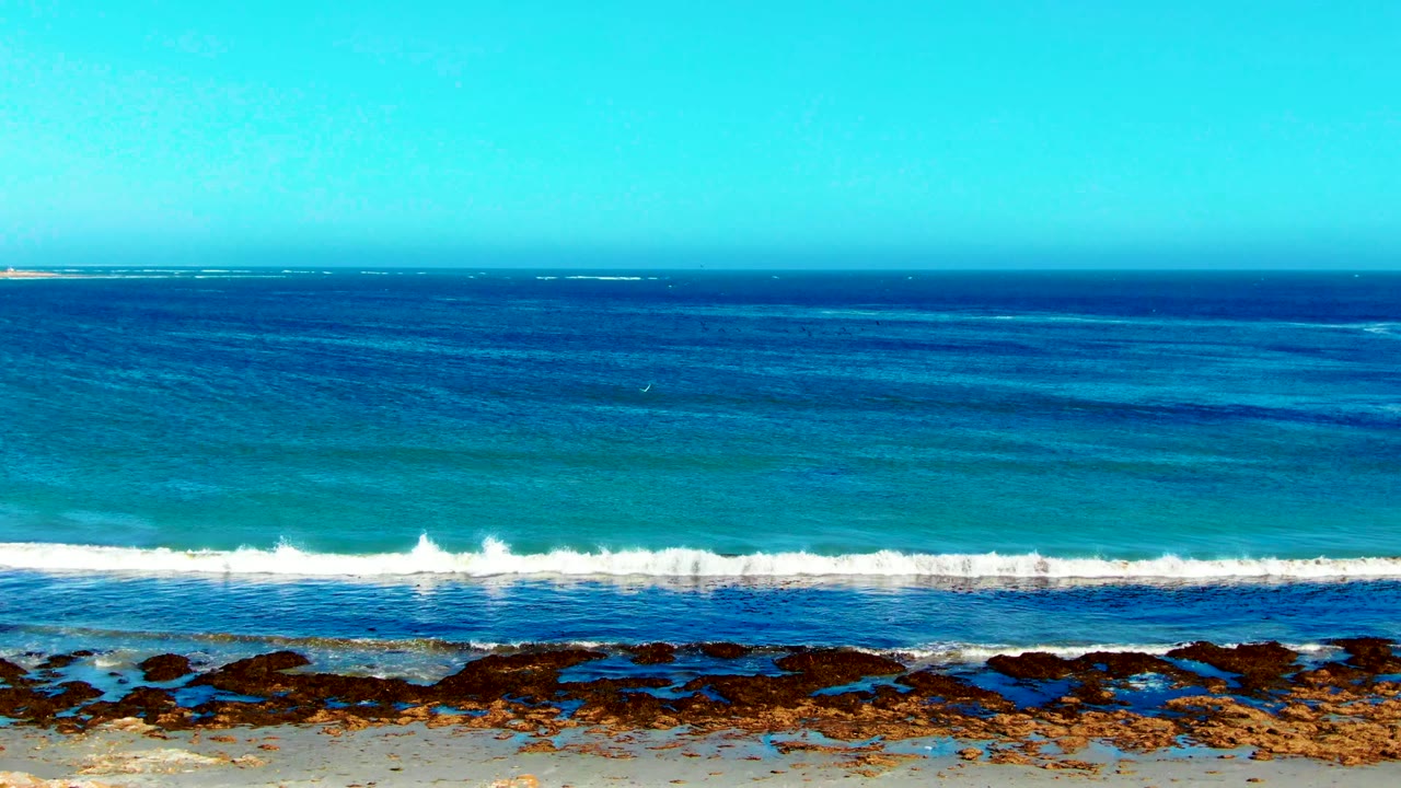 Ocean horizon and white surf line above a rocky sandy shore