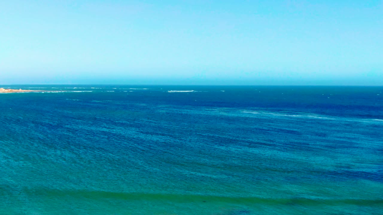 Blue water surface with bands of waves near the horizon