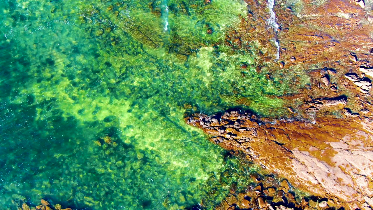 Shallow green water with rocks and faint foam