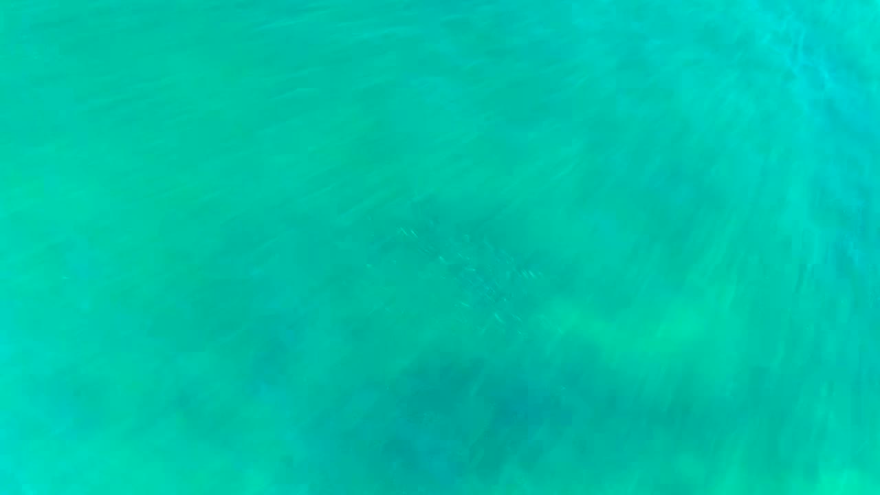 Overhead turquoise ocean water in La Bocana, Baja California Sur, with faint seabed texture and no visible people at the opening moment.