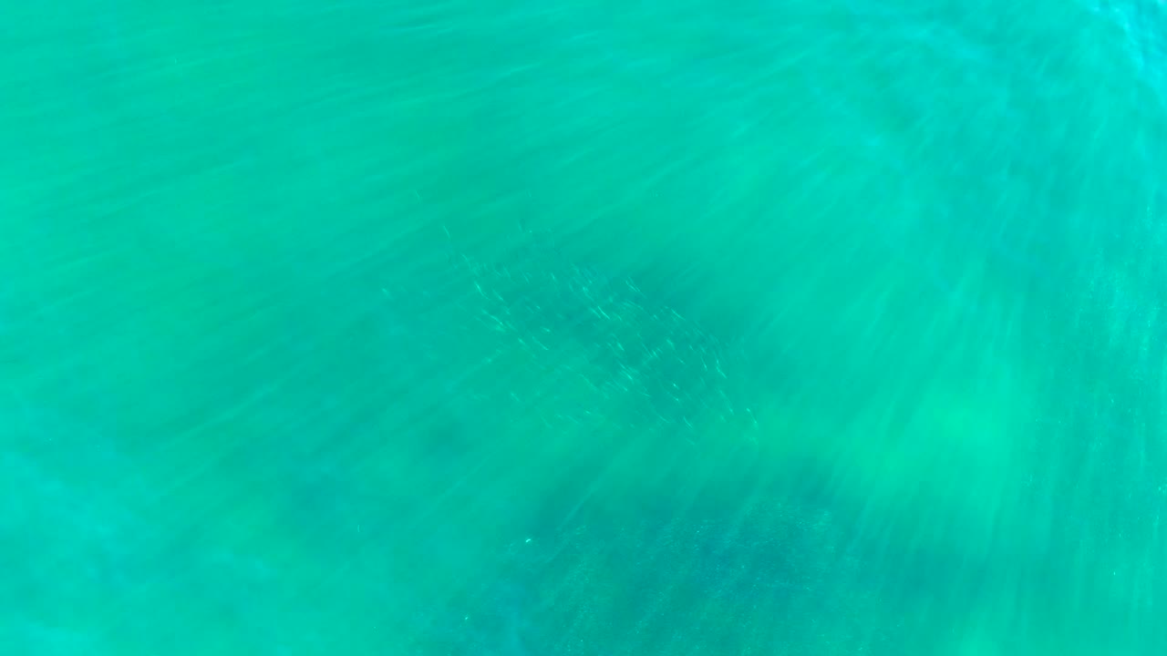Turquoise shallow ocean water in La Bocana, Baja California Sur, with brighter sunlit veils near the right edge and no visible people.