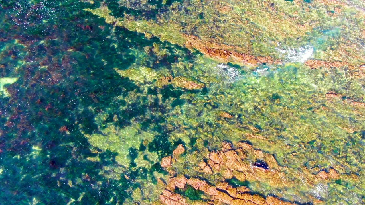 Rock formations under green-blue coastal water