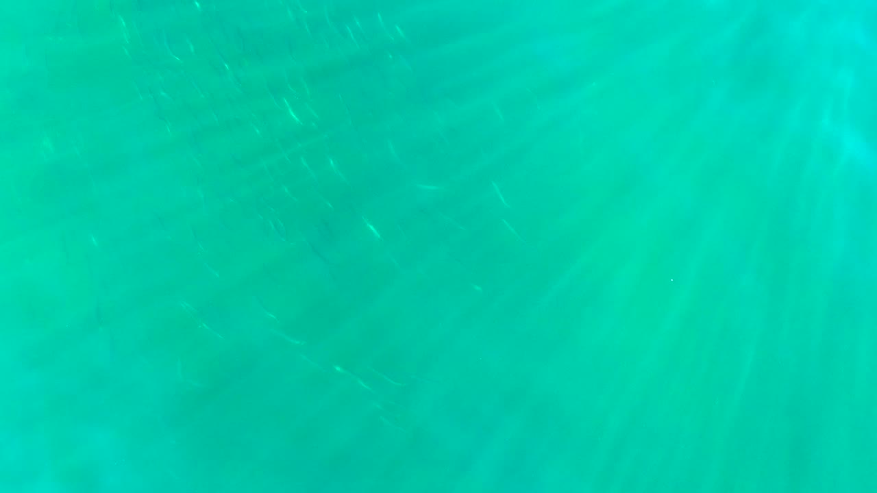 Turquoise water in La Bocana, Baja California Sur, with faint bright streaks shifting across the frame and no visible people.