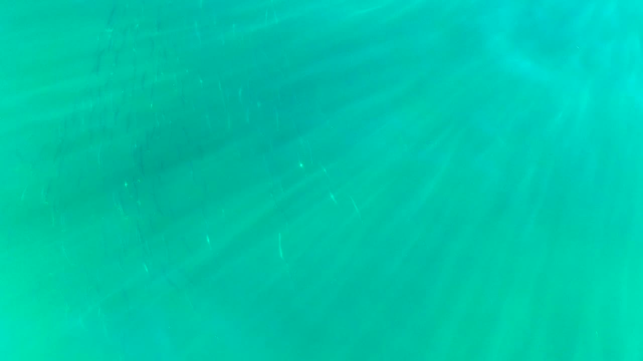 At 0:00, clear turquoise water from La Bocana fills the frame with faint diagonal sunlight rays and no visible people.