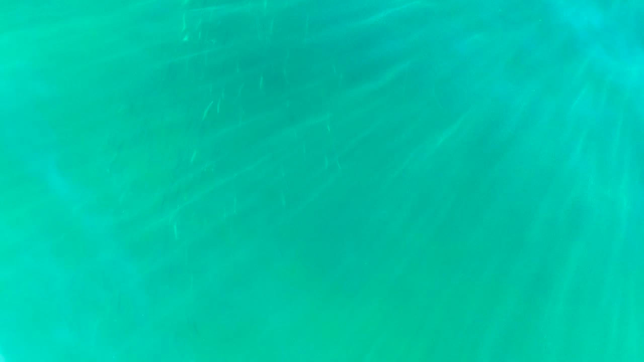 Underwater turquoise field in La Bocana, Baja California Sur, with diagonal sun rays diffused through clear water and no visible people.