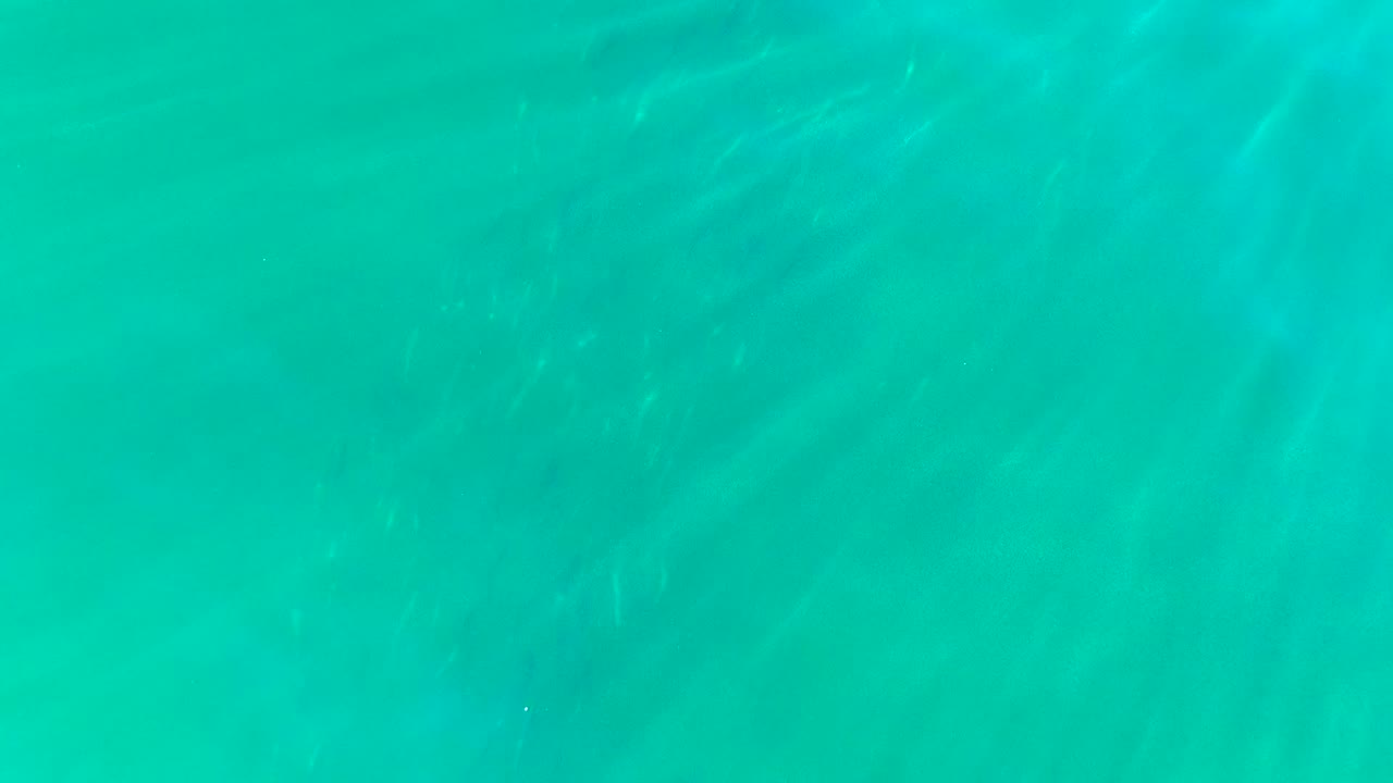 Turquoise shallow-looking water in La Bocana, Baja California Sur, with brighter caustic lines visible beneath the surface, no visible people.