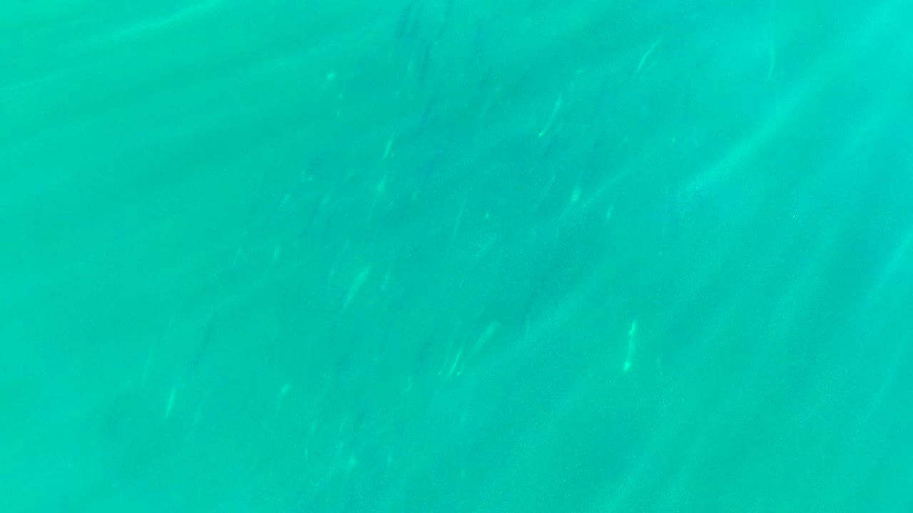 Clear turquoise water with subtle darker patches below the surface.