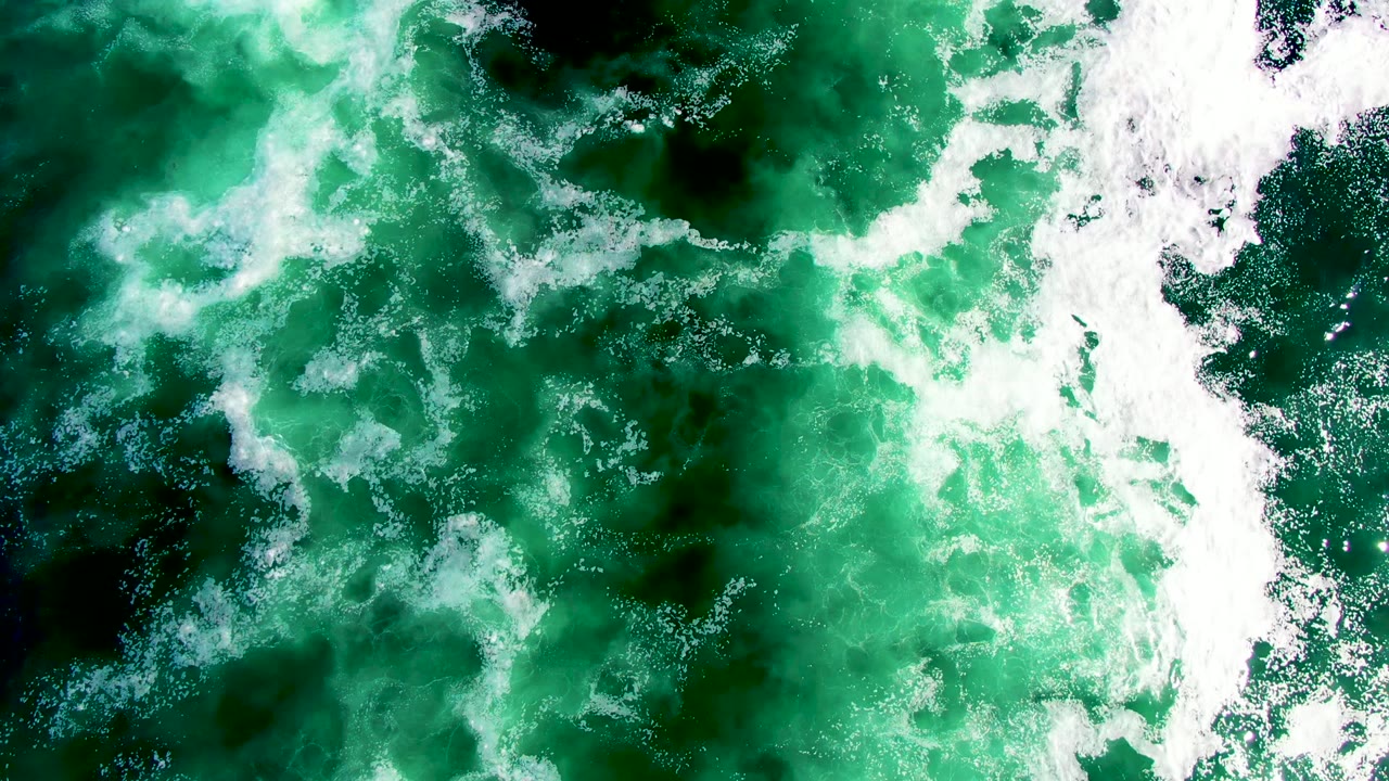 Aerial view of the La Bocana ocean surface where a vertical strip of whitewater divides darker green wave patches, with no visible people.