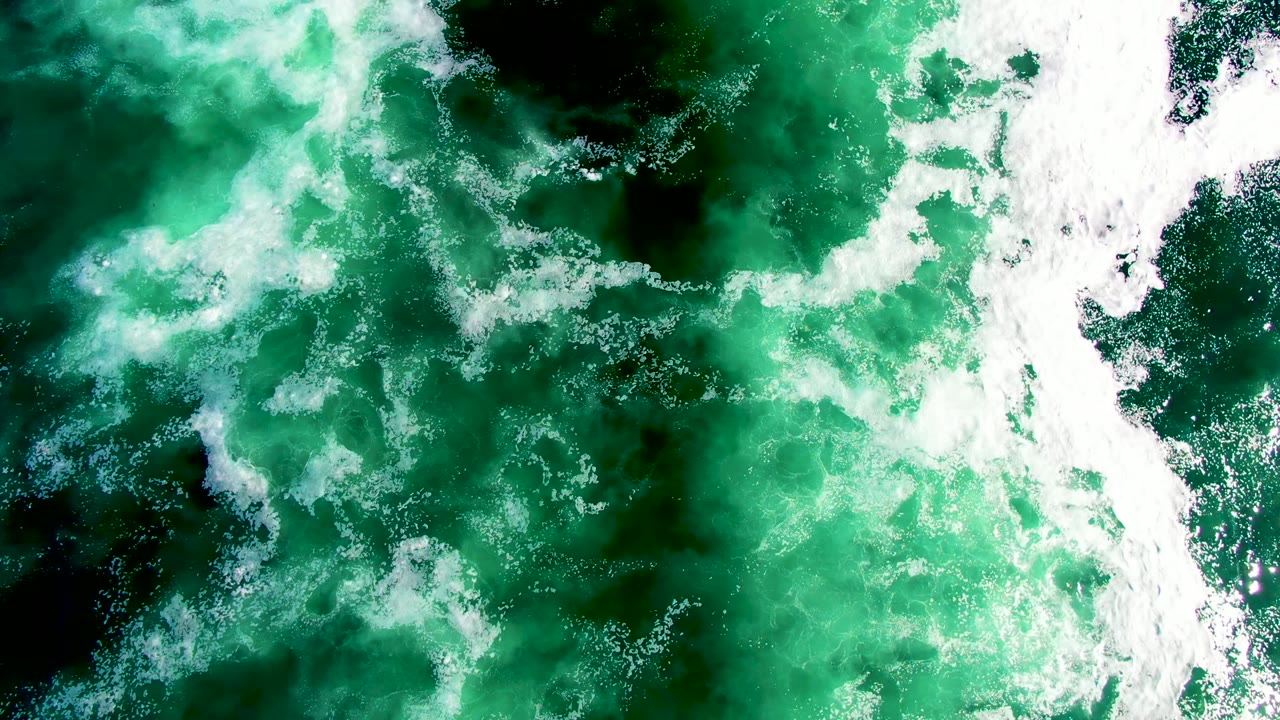 Top-down La Bocana surf frame with mottled emerald water, white foam streaks, and no visible people or shoreline.