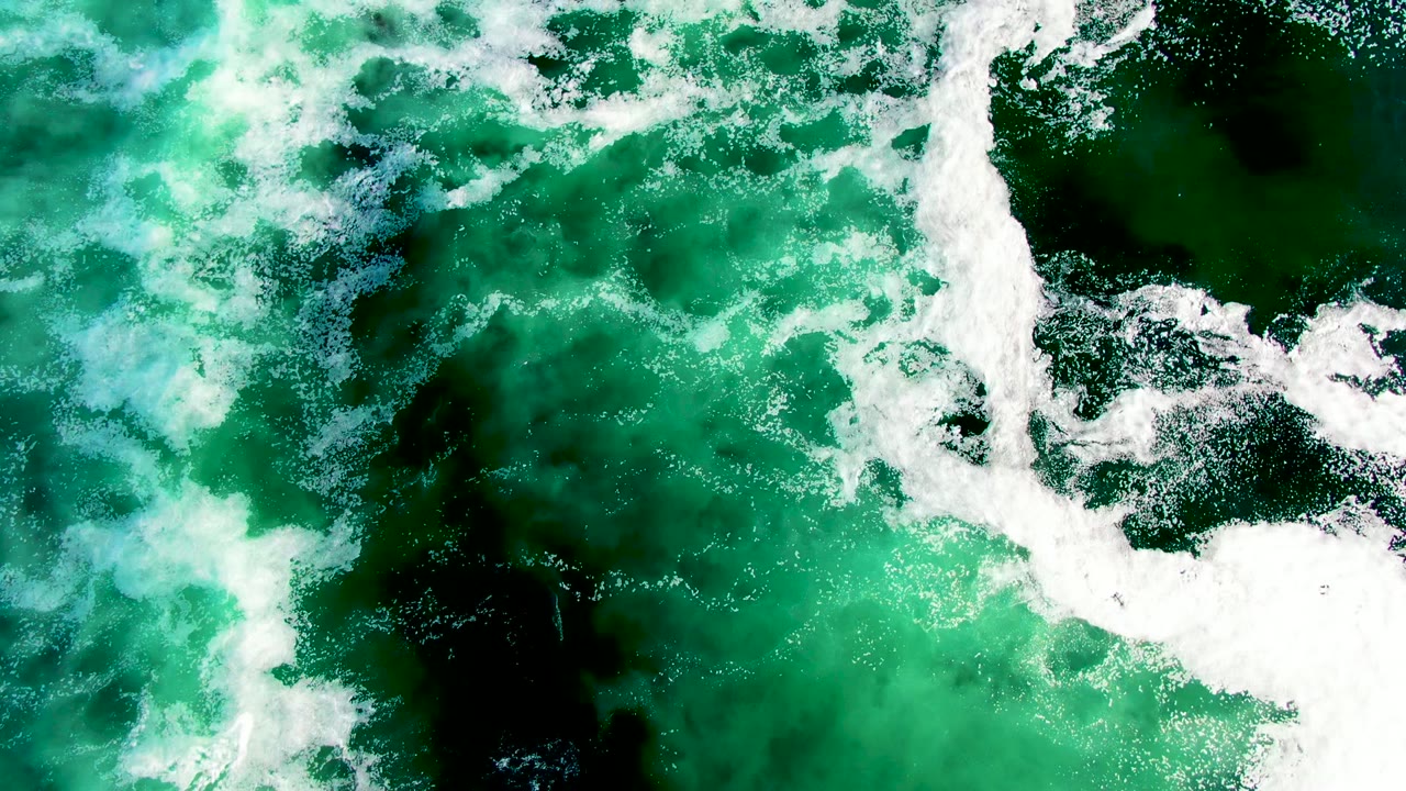 White wave foam cutting across green ocean surface
